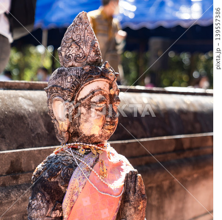 Weathered female guardian figure stands within a sacred temple site surrounded by historic stone structures and cultural heritage architecture. 139557386