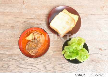 beef curry or Mussamun Indian food with slice potato and tomato on bowl eat couple fresh cos lettuce salad and grilled butter toast bread beef curry or Mussamun Indian food with slice potato and tomato on bowl eat couple fresh cos lettuce salad and grilled butter toast bread 139557639