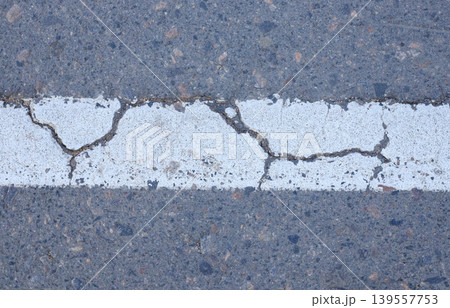 Worn road markings on a road with visible signs of aging and cracks. Detail of urban road markings on asphalt Worn road markings on a road with visible signs of aging and cracks. Detail of urban road markings on asphalt 139557753