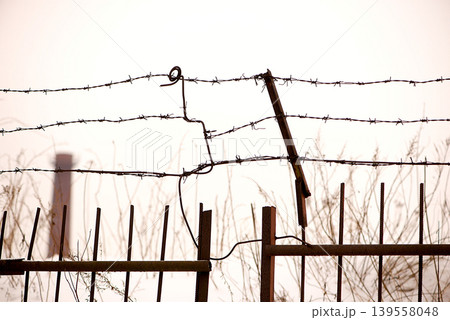 Broken Barbed Wire Fence Against Pale Sky Broken Barbed Wire Fence Against Pale Sky 139558048