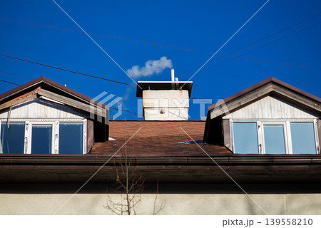 Symmetrical rooftops with chimney against blue sky Symmetrical rooftops with chimney against blue sky 139558210