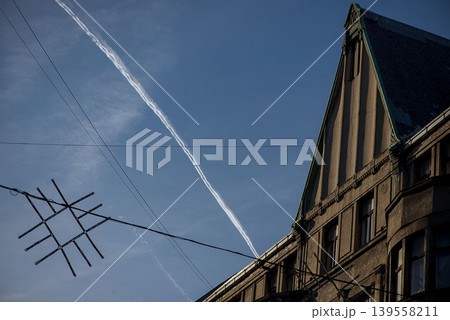 Long White Contrail Crossing Historic City Rooftops Long White Contrail Crossing Historic City Rooftops 139558211