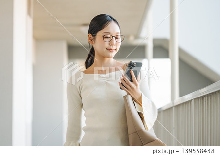 マンションの通路でスマホを見る若い女性 マンションの通路でスマホを見る若い女性 139558438