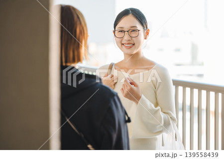 マンションの通路でママ友と世間話をする若い女性 マンションの通路でママ友と世間話をする若い女性 139558439