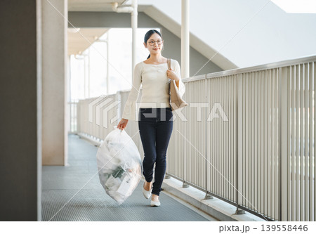 朝出勤時にゴミを出しに行く女性 139558446
