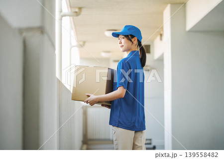 マンションに荷物を運ぶ宅配業者の若い女性 139558482