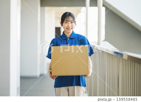 マンションに荷物を運ぶ宅配業者の若い女性 139558485