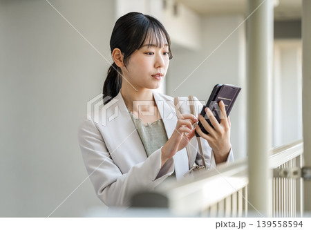 マンションの廊下でスマホを見る若い女性 139558594