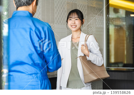 マンションのエントランスで管理人と話す若い女性 マンションのエントランスで管理人と話す若い女性 139558626