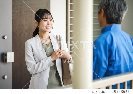 マンションの廊下で管理人と話す若い女性 139558628