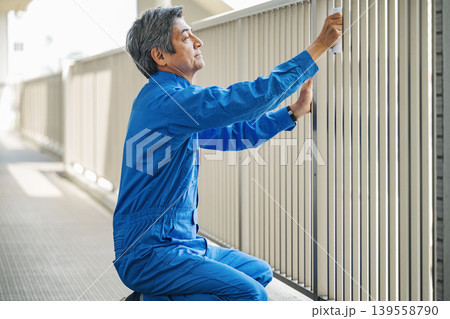 マンションの手すりを雑巾で掃除する管理人のシニア男性 139558790