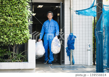 ゴミ出しをするマンション管理人のシニア男性 ゴミ出しをするマンション管理人のシニア男性 139558814