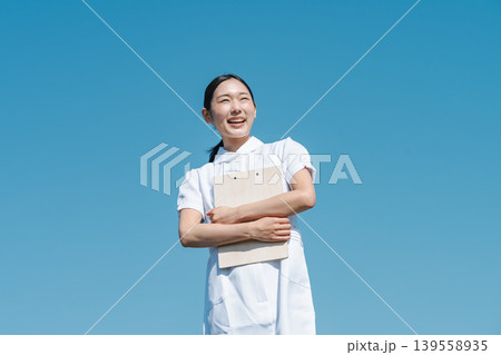 青空を背景に立つ看護師の若い女性 青空を背景に立つ看護師の若い女性 139558935