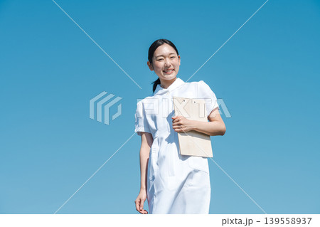 青空を背景に立つ看護師の若い女性 青空を背景に立つ看護師の若い女性 139558937