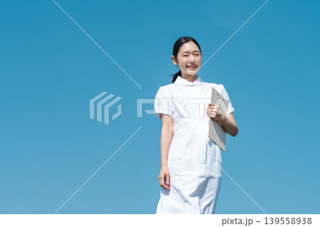 青空を背景に立つ看護師の若い女性 青空を背景に立つ看護師の若い女性 139558938