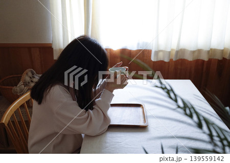 髪も整えず部屋着のまま白湯を飲む女性　朝にゆっくり調子を整えるイメージ 139559142