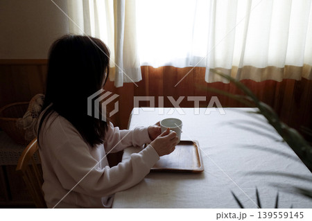 髪も整えず部屋着のまま白湯を飲む女性　朝にゆっくり調子を整えるイメージ 139559145