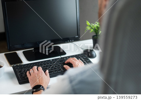 Man typing on keyboard at home office desk Man typing on keyboard at home office desk 139559273