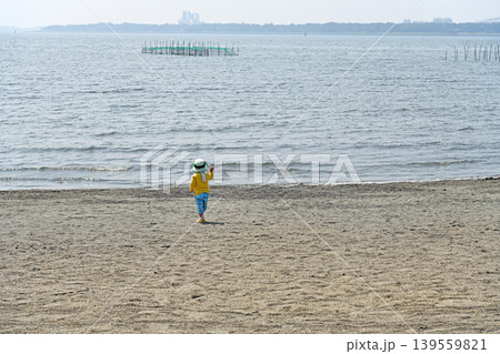 広い海へ歩み寄る子供　未来への好奇心と冒険心を育む穏やかな浜辺の光景 139559821