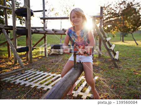 Happy girl, portrait and riding seesaw in park sunset for fun holiday, weekend or outdoor break in nature. Face of female person, kid or child smile on playground for childhood activity outside 139560084