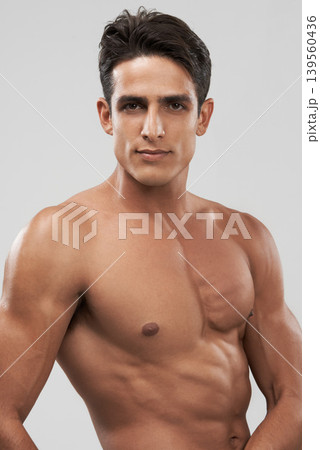 Man, shirtless and portrait or bodybuilder pride in studio, abs and fitness by gray background. Male person, confident and strong core or muscular abdomen, face and results or progress from exercise Man, shirtless and portrait or bodybuilder pride in studio, abs and fitness by gray background. Male person, confident and strong core or muscular abdomen, face and results or progress from exercise 139560436