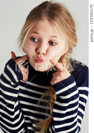 Fashion, goofy and girl kid in a studio with casual, cool and stylish jersey outfit. Silly, comic and funny young child model with trendy youth style and positive attitude by gray background. 139560578