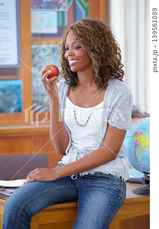 Happy black woman, teacher and eating apple for natural diet, nutrition or food for snack in classroom. African female person or educator smile with red organic fruit for health and wellness in class Happy black woman, teacher and eating apple for natural diet, nutrition or food for snack in classroom. African female person or educator smile with red organic fruit for health and wellness in class 139561089