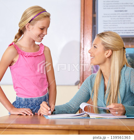 Teacher, student and grading paper in classroom, education and learn with portfolio, mark test or feedback. Teaching for development, exam and study, explain subject with woman and girl kid in class 139561363