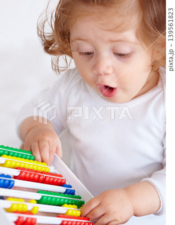 Abacus, surprise and girl baby learning, playing and teaching for child development on bed. Maths, toy and closeup of young kid, infant or toddler counting for education in bedroom at modern home. 139561823