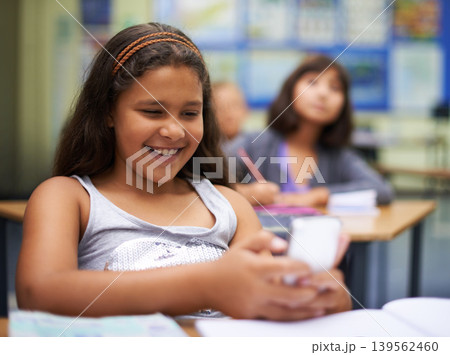 School, students or girl with a phone for texting, gossip or message notification in classroom. News, sharing or happy child with a funny meme on mobile app or social media for online distraction 139562460