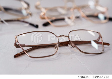 Close-up of stylish metal eyeglasses with clear lenses on a light gray surface, fashion accessory concept Close-up of stylish metal eyeglasses with clear lenses on a light gray surface, fashion accessory concept 139563758