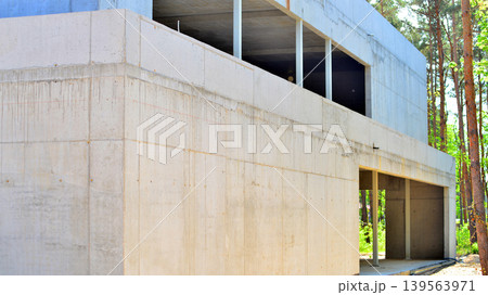 An abandoned concrete building under construction surrounded by a forest. An unfinished two-story modernist structure. An abandoned concrete building under construction surrounded by a forest. An unfinished two-story modernist structure. 139563971