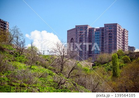 City towers rise above lush spring trees under blue sky City towers rise above lush spring trees under blue sky 139564105