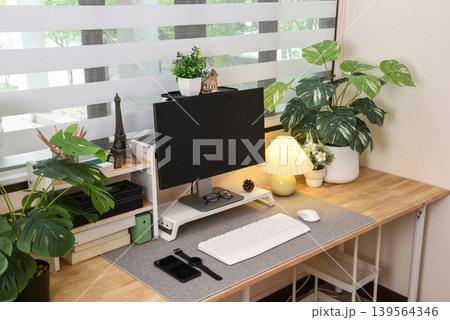 Modern contemporary home office setup with wooden desk surrounded by green plant Modern contemporary home office setup with wooden desk surrounded by green plant 139564346