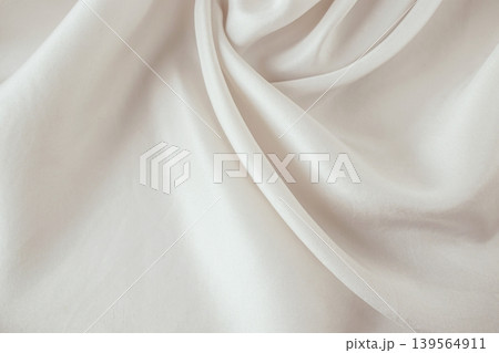 Beige silk fabric texture background. Close-up of elegant light beige silk fabric with soft folds and draperies. Beige silk fabric texture background. Close-up of elegant light beige silk fabric with soft folds and draperies. 139564911