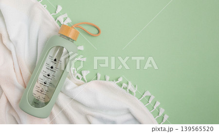 Water bottle and towel on a light green background. Water bottle and towel on a light green background. 139565520
