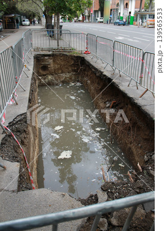 The hole in the road was created to repair underground utilities. 139565533
