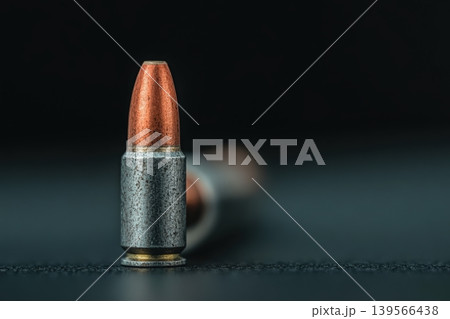 Copper and silver bullet stands upright on a dark, textured surface 139566438