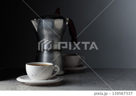 Cup of espresso and classic Italian aluminium moka pot on a gray stone table. Cup of espresso and classic Italian aluminium moka pot on a gray stone table. 139567337