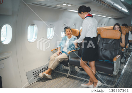 Senior woman receiving in flight service from flight attendant in business class airplane seat Senior woman receiving in flight service from flight attendant in business class airplane seat 139567561