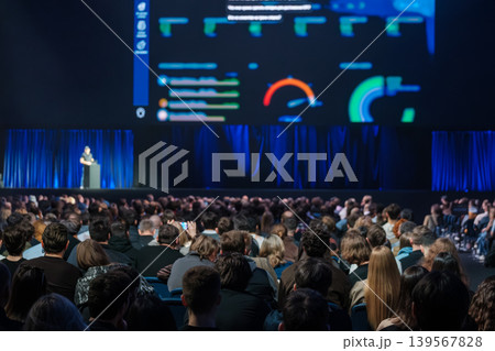 Conference audience watching speaker present data dashboards on large screen at tech presentation event 139567828