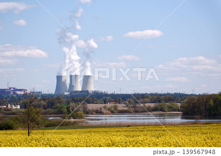 Cooling towers with steam on sky at nuclear power plant with pond and trees nature foreground, Temelin, Czech Republic, energy self-sufficiency, greenhouse emission reduction, global warming concept 139567948