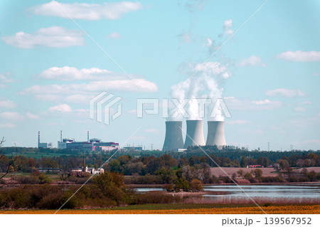 Cooling towers with steam on sky at nuclear power plant with pond and trees nature foreground, Temelin, Czech Republic, energy self-sufficiency, greenhouse emission reduction, global warming concept Cooling towers with steam on sky at nuclear power plant with pond and trees nature foreground, Temelin, Czech Republic, energy self-sufficiency, greenhouse emission reduction, global warming concept 139567952