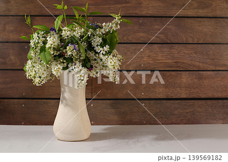 Still life with beautiful spring branches of blooming bird cherry in vase against an elegant background.Abstract floral arrangement and banner for the screen. A floral holiday card Still life with beautiful spring branches of blooming bird cherry in vase against an elegant background.Abstract floral arrangement and banner for the screen. A floral holiday card 139569182