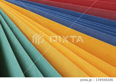 Color paper sheets form diagonal layered stripes in teal, yellow, orange, blue, red tones. Natural background with paper texture for design, craft, education, color layout, copy space Color paper sheets form diagonal layered stripes in teal, yellow, orange, blue, red tones. Natural background with paper texture for design, craft, education, color layout, copy space 139569286