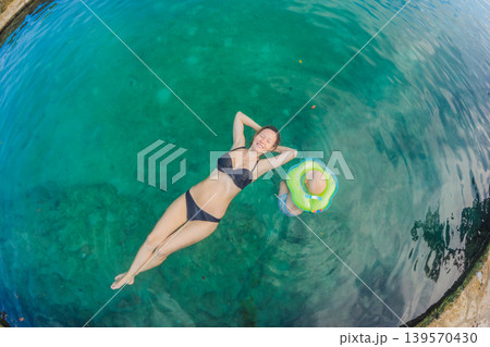 Mother and little son swimming together in a Mexican cenote with crystal clear water. Family travel, childhood adventure and tropical wellness lifestyle concept Mother and little son swimming together in a Mexican cenote with crystal clear water. Family travel, childhood adventure and tropical wellness lifestyle concept 139570430