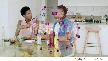 Holding burger woman left and holding sandwich man right conversing at glass table, magenta overlay 139571628