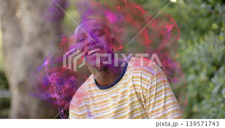 Laughing man wearing yellow white striped T-shirt in park, magenta purple powder bursting on face Laughing man wearing yellow white striped T-shirt in park, magenta purple powder bursting on face 139571743
