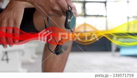Tightening swimmer holding mirrored goggles strap in dark briefs poolside, block 4 waveform Tightening swimmer holding mirrored goggles strap in dark briefs poolside, block 4 waveform 139571759