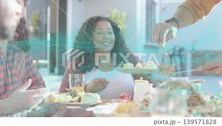 Smiling woman receiving pastry from serving tray while holding glass of juice at dining table 139571828
